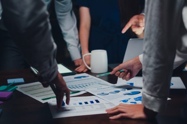 Millennial Asia businessmen and businesswomen meeting brainstorming ideas about new paperwork project colleagues working together planning success strategy enjoy teamwork in small modern night office.